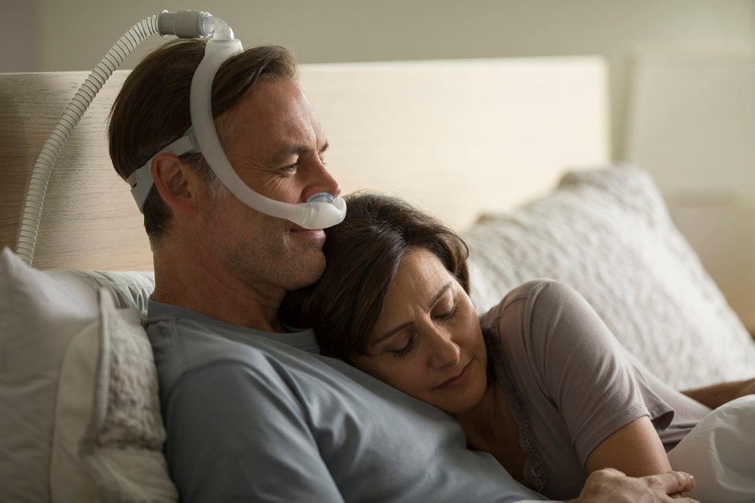 man using a cpap machine being held by his wife